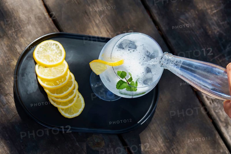 Top view of a bottle of tonic poured over a glass with ice