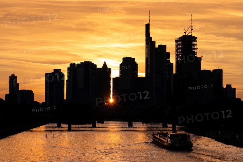 A ship sails at sunset on the Main towards the silhouette of Frankfurt's banking skyline