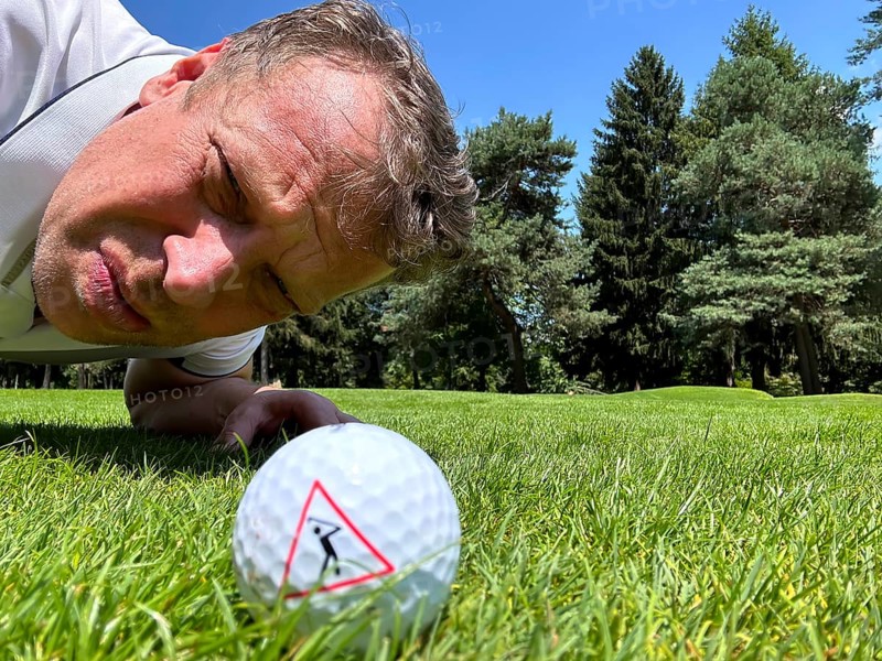 Golfer Looking at a Golf Ball with Warning Sign on the Fairway in a Sunny Day in Switzerland