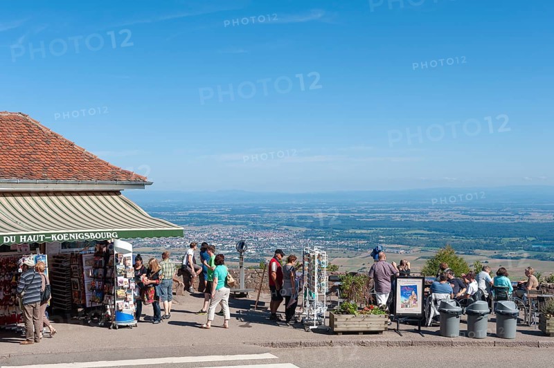Tourists at the viewpoint in front of the Chateau du Haut Koenigsbourg. In the background the Upper Rhine Plain and the hilly landscape of the Black Forest