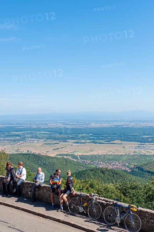 Tourists at the viewpoint in front of the Chateau du Haut Koenigsbourg. In the background the Upper Rhine Plain and the hilly landscape of the Black Forest