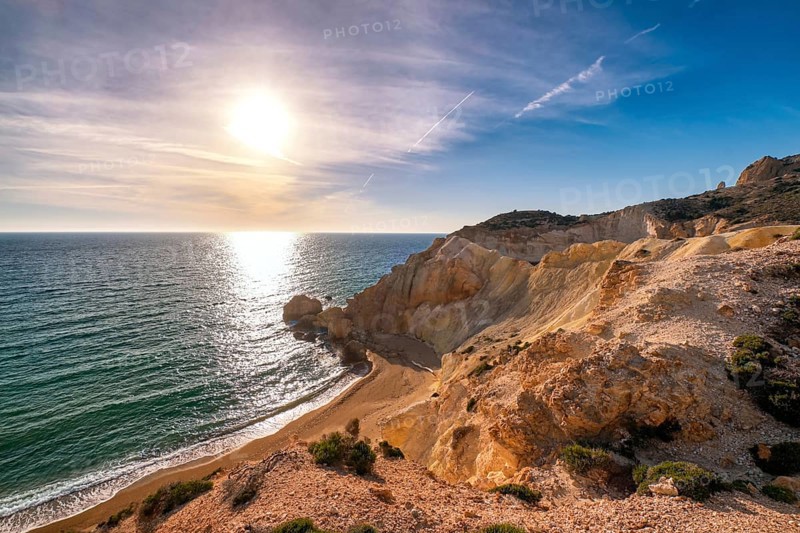 Beautiful low sun view of secluded and remote beach on sunny evening. High yellow cliffs