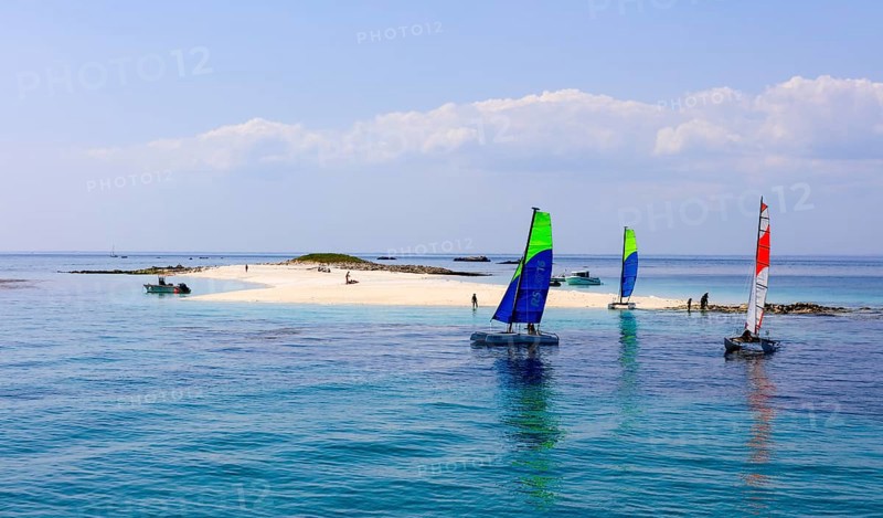 Sailing catamarans of the sailing school Les Glenans in front of the sandy beach of Ile de Guiriden