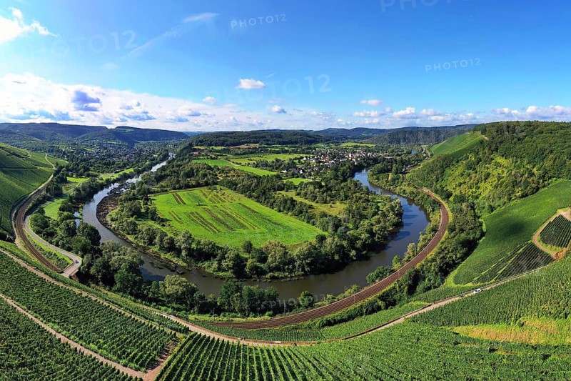 Wiltinger Saarbogen. The river winds through the valley and is surrounded by vineyards and green forests. Kanzem