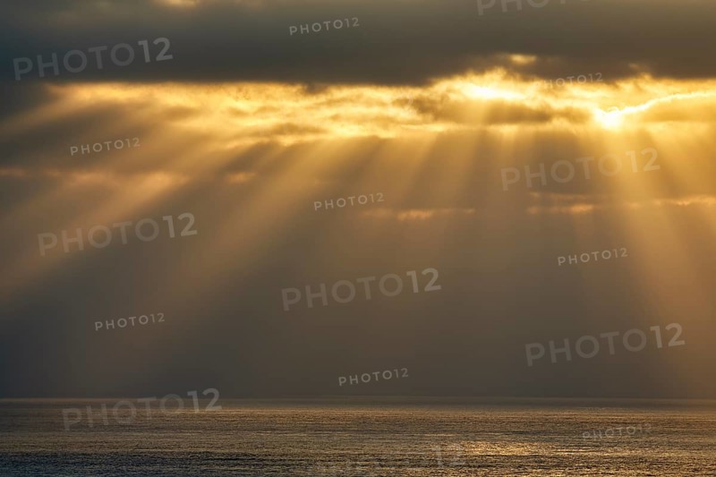 Sunbeams shining through clouds by the sea
