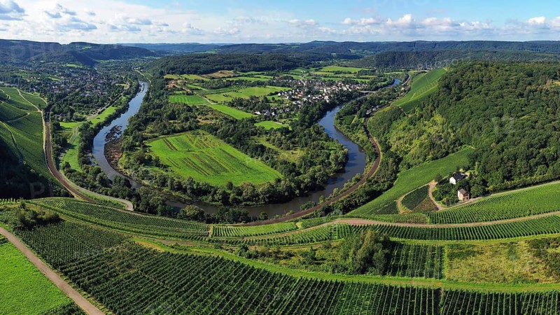 Wiltinger Saarbogen. The river winds through the valley and is surrounded by vineyards and green forests. Kanzem