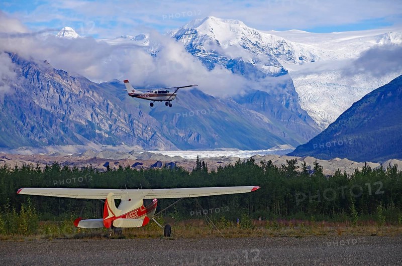 Two small bush planes in front of huge glaciers