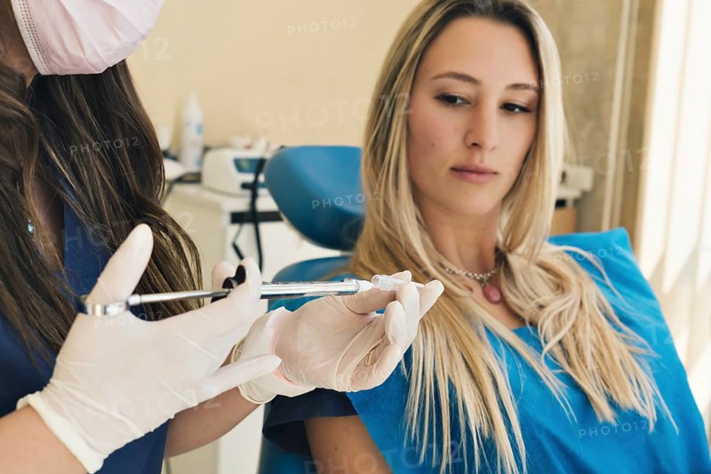 Dentist prepares anesthesia in dental office in background patient looks at injection with trepidation. Selective focus