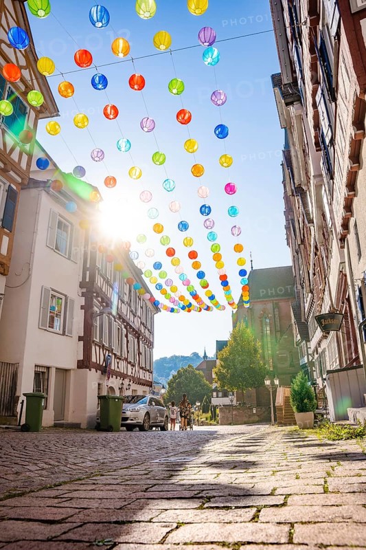 Colourful lanterns hanging in alleyway alley between half-timbered houses