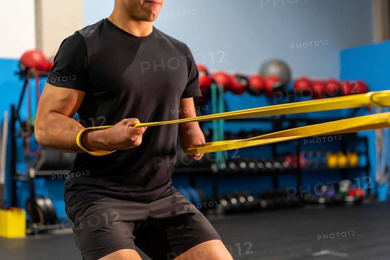 Unrecognizable sportive man with an arm amputated training in a gym using a rubber band