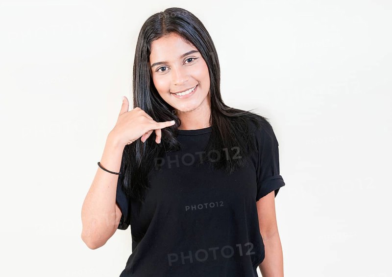Smiling young girl gesturing call me with hand isolated. Happy latin girl gesturing call with fingers isolated
