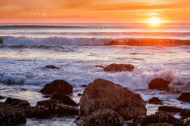 Atlantic ocean sunset with waves and rocks at Costa da Caparica