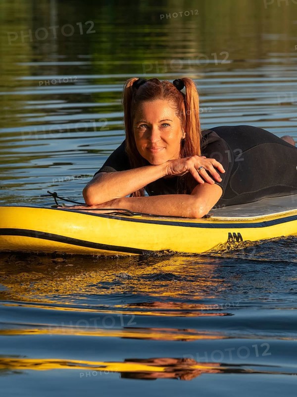 Woman lying relaxed on standup paddle board in lake