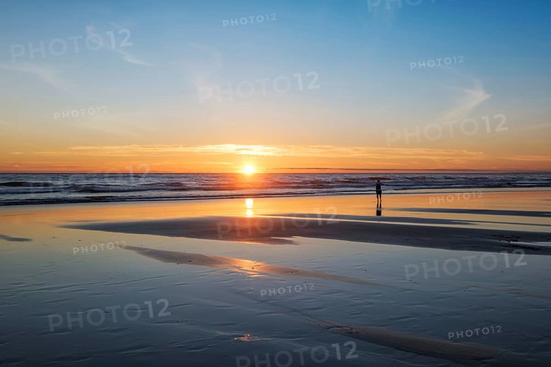 Atlantic ocean sunset with photographer silhouette taking images of surging waves at Fonte da Telha beach