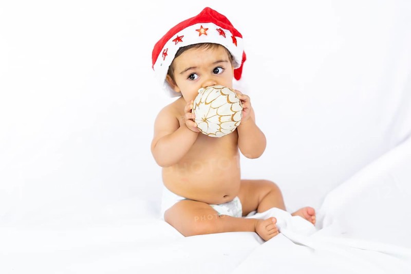 A baby boy with a red Christmas hat on a white background