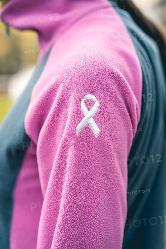Side view of a woman wearing a sweatshirt with an embroidered cancer awareness ribbon. Vertical Shot