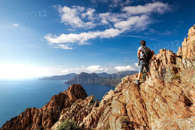 A hiker stands on a rock in the Calanche