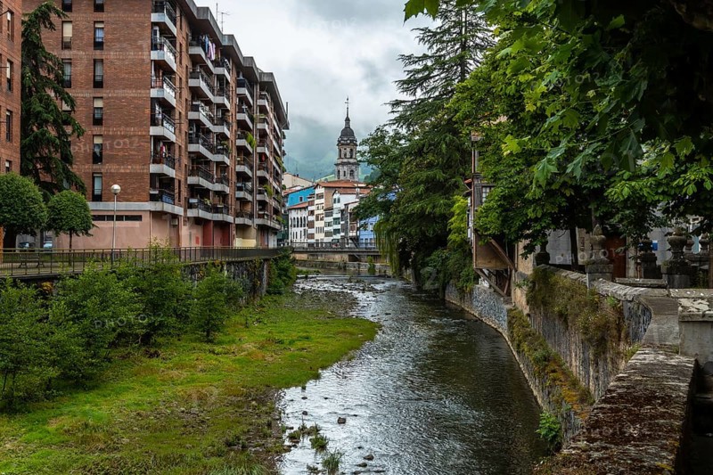 Traditional houses in the town of Azkoitia next to the Urola river and Church of Santa Maria La Real in the background