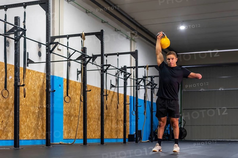 Portrait with copy space of a disabled sportive man lifting a kettlebell in a cross training gym
