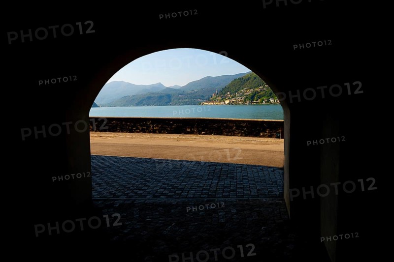 Old Beautiful Street Tunnel with Arch from Brusino Arsizio on the Waterfront in a Sunny Summer Day and with Lake Lugano and Mountain View over Morcote