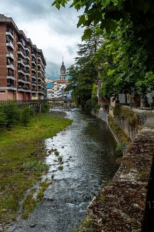 Traditional houses in the town of Azkoitia next to the Urola river and Church of Santa Maria La Real in the background