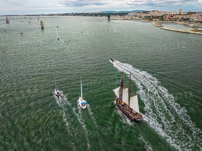Aerial drone view of tall ships with sails sailing in Tagus river towards the Atlantic ocean in Lisbon