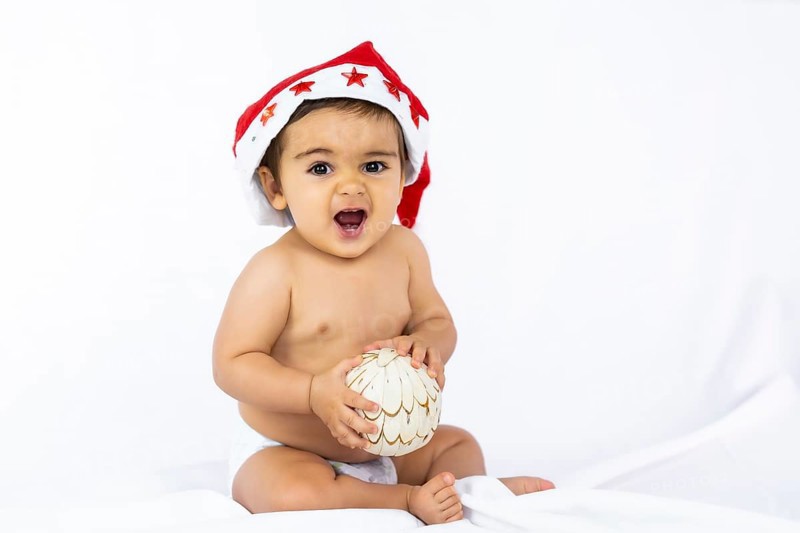 A baby boy with a red Christmas hat on a white background