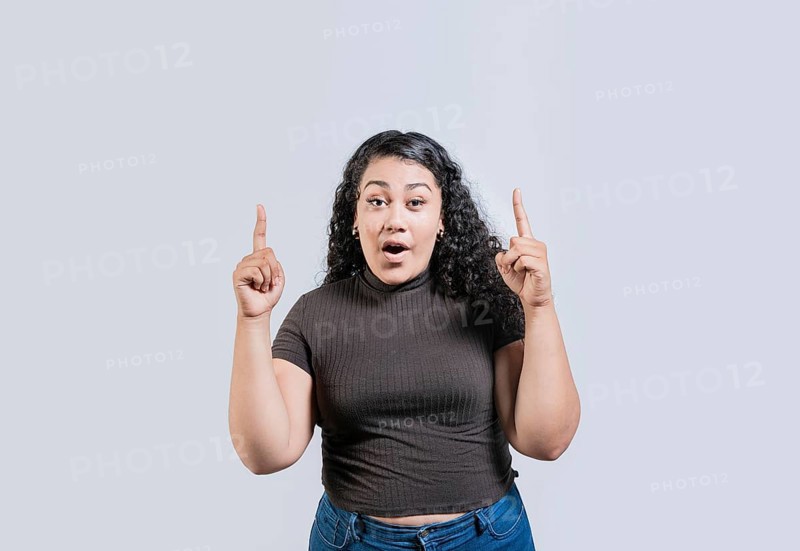 Young latin girl amazed pointing a promotion up isolated. Young curly-haired woman pointing up. Latin people pointing up