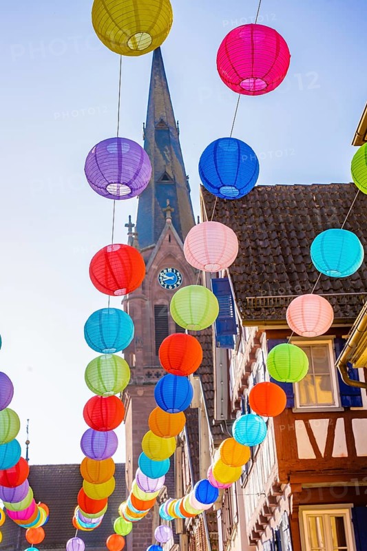 Colourful lanterns hanging in alleyway alley between half-timbered houses