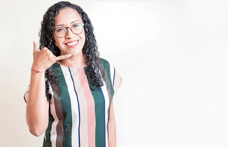 Happy girl in glasses gesturing call me with hand isolated. Latin woman in glasses gesturing call with fingers isolated