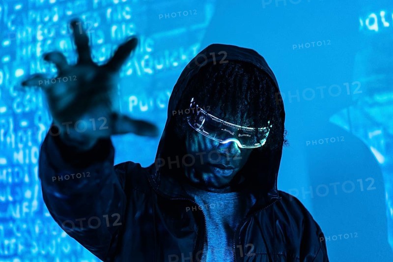 Studio photo with blue neon light of a man grabbing the future wearing augmented reality goggles