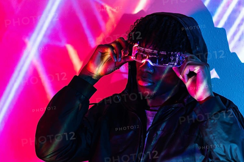 Studio portrait with purple and blue neon lights of an afro futuristic cool man in a metaverse realisty