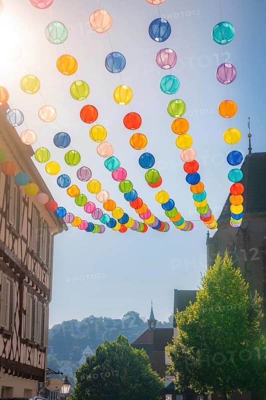 Colourful lanterns hanging in alleyway alley between half-timbered houses