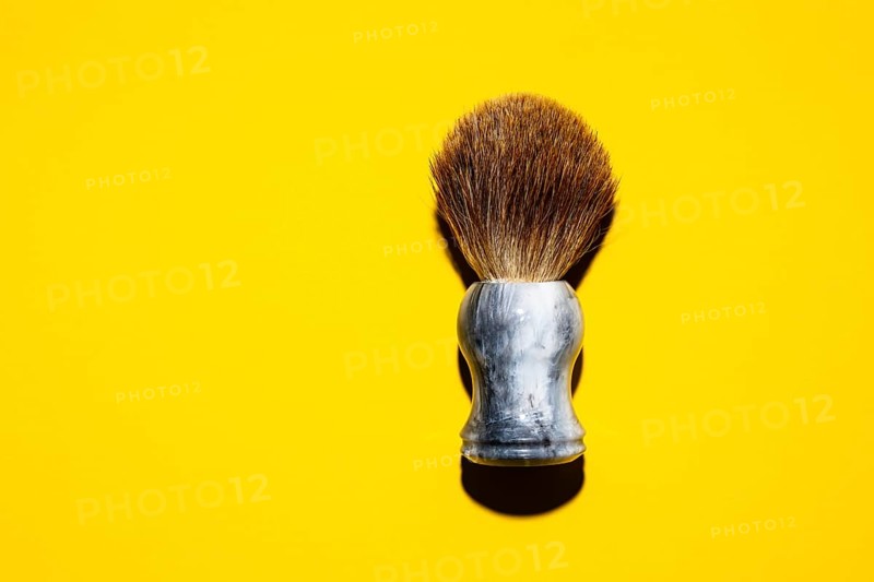 Top view of a shaving brush against a yellow background