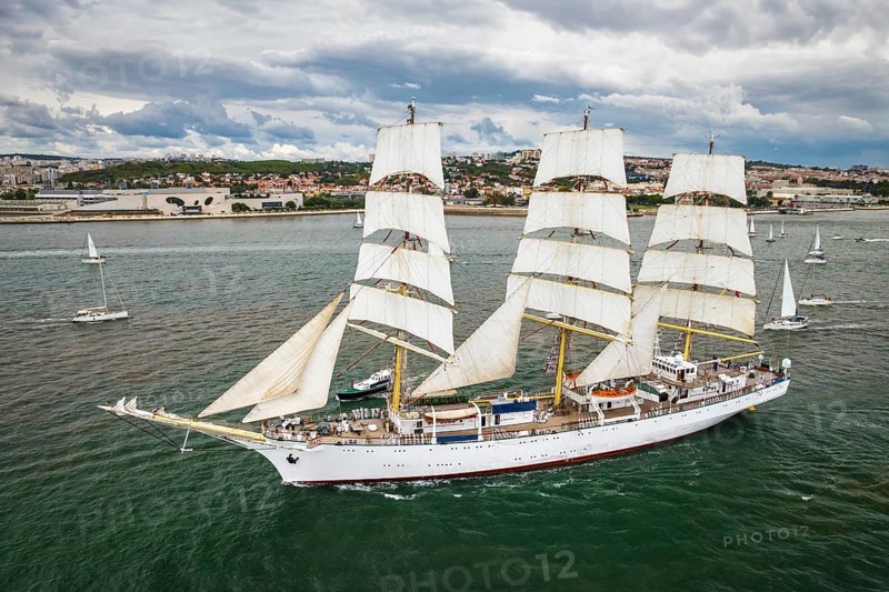 Aerial drone view of tall ships with sails sailing in Tagus river towards the Atlantic ocean in Lisbon