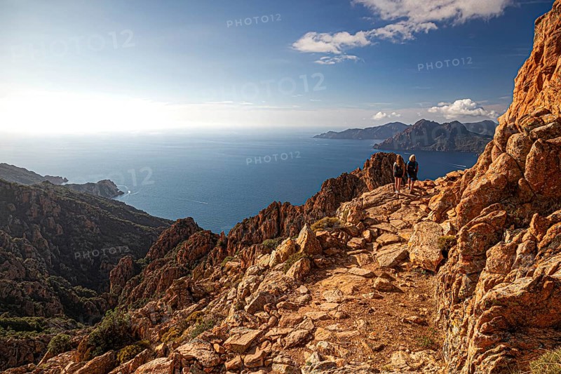 Two woman walking in the Calanche a bizarre rocky landscape on the south coast of the Gulf of Porto in the Regional nature park Park Corsica France Europe