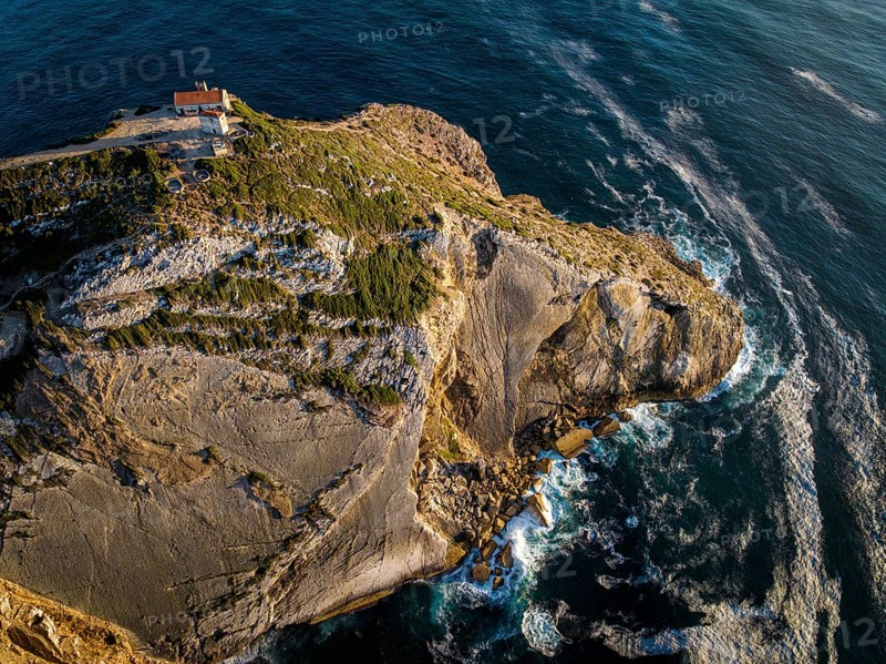 Aerial drone view of Cabo Espichel cape Espichel on Atlantic ocean at sunset with ruins