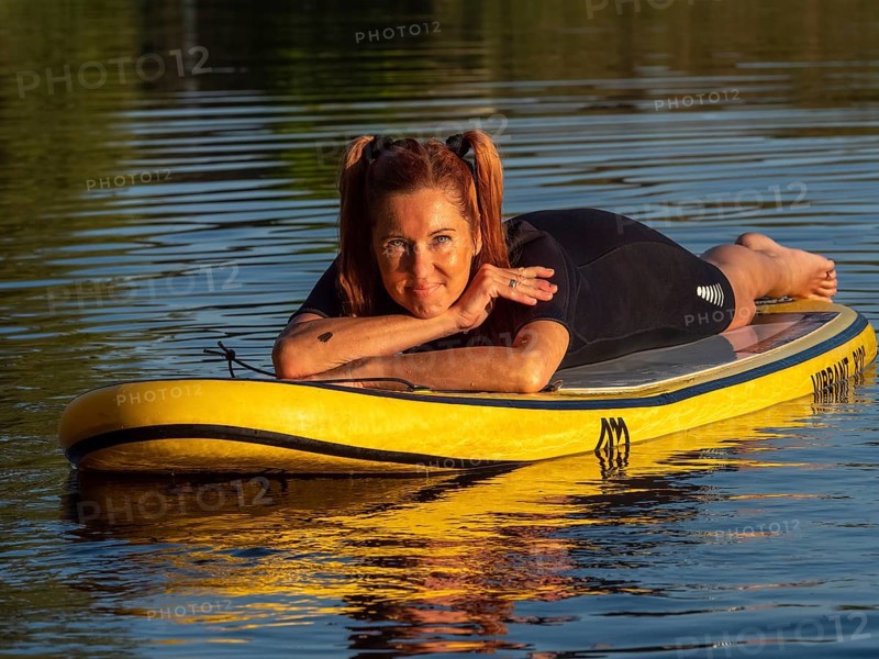 Woman lying relaxed on standup paddle board in lake