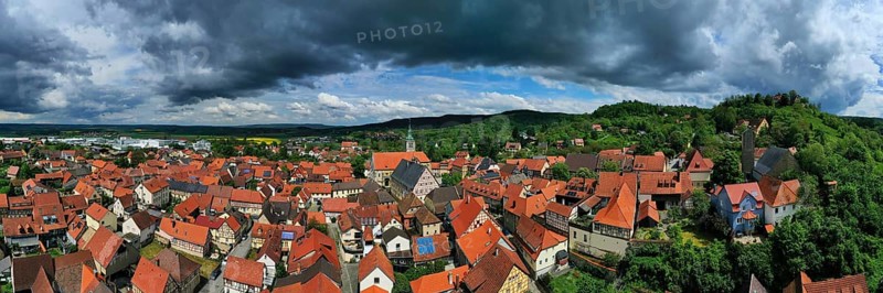 Aerial view of Koenigsberg in Bavaria. The city is surrounded by hills and forests. The sky is cloudy and dark