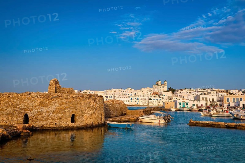 Traditional Greek whitewashed houses and church of Dormition of Mother of God as local landmark on hilltop by seafront on sunny day
