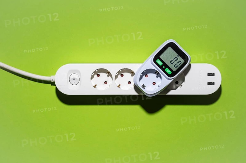 Top view of an energy cost meter in a power strip against a green background