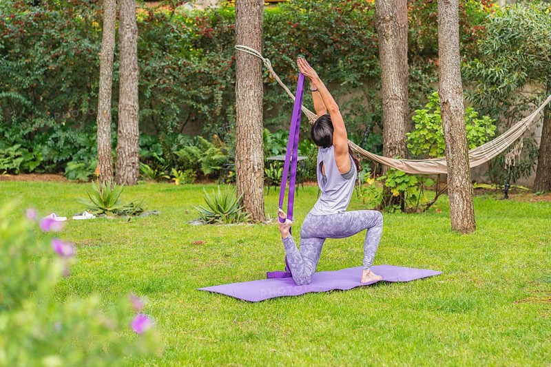 Back view of a woman exercising yoga with strap. Copy space