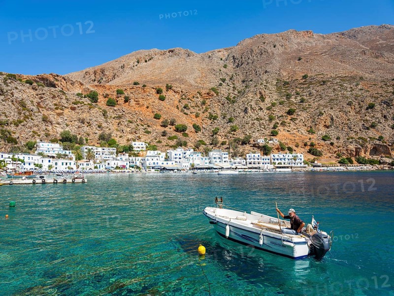 Small fishing boat in the harbour of Loutro below a rocky mountain