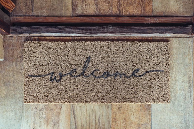 Welcome mat in front of door over wooden floor