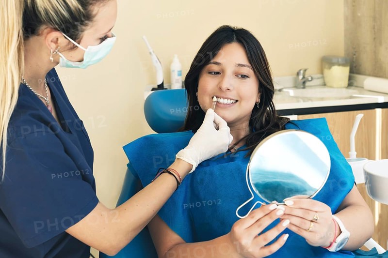 Female dentist checking on female patient teeth color
