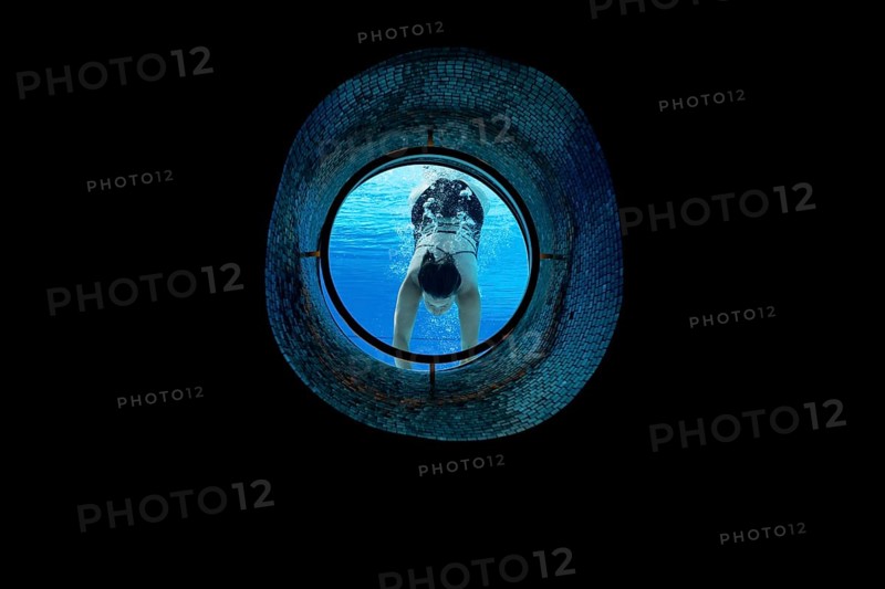 Woman Swimming in the Ship Porthole in Underwater in Swimming Pool in a Sunny Day in Switzerland