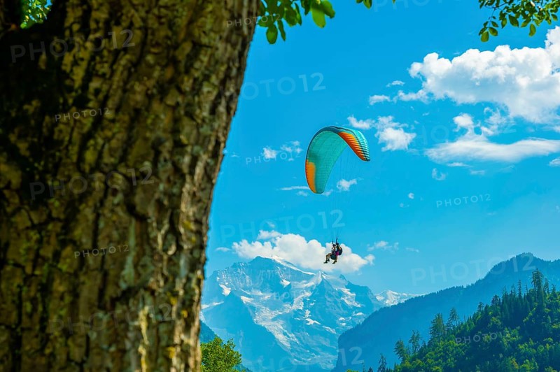 Couple Paragliding in front Of Snow Capped Jungfraujoch Mountain in a Sunny Day in Interlaken