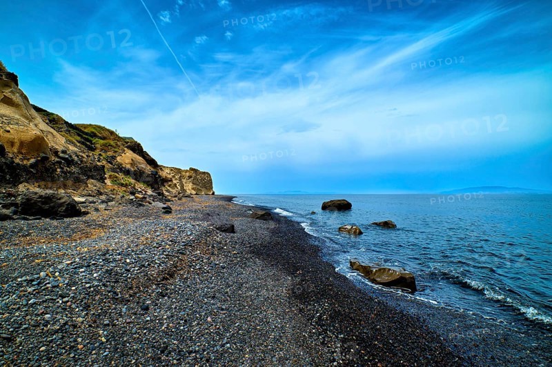 Dramatic landscape of blue sea or ocean waves rolling on rocky volcanic beach on cloudy day. Blue sky