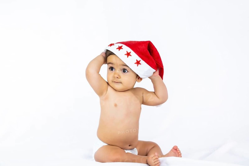 A baby boy with a red Christmas hat on a white background