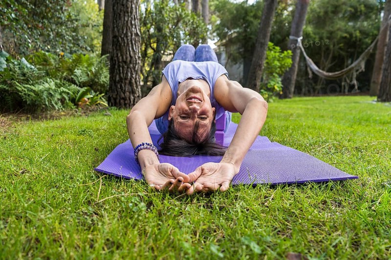 Happy smiling woman lying on yoga blocks while looking at camera
